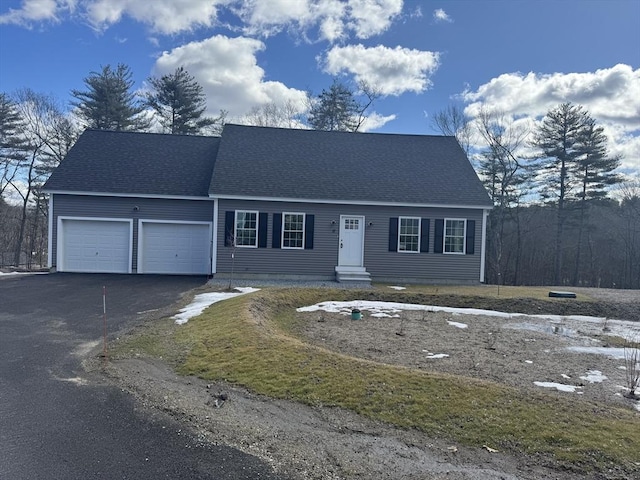 cape cod-style house with a garage, roof with shingles, and aphalt driveway