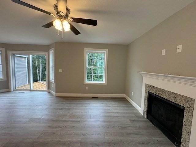 unfurnished living room featuring ceiling fan, baseboards, wood finished floors, and a high end fireplace