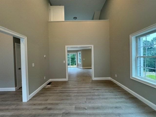 unfurnished room with wood finished floors, a towering ceiling, and baseboards