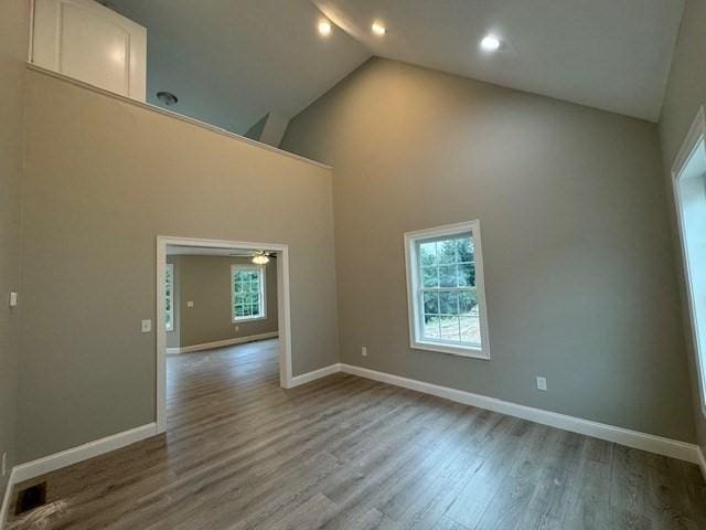 unfurnished room featuring high vaulted ceiling, baseboards, and wood finished floors