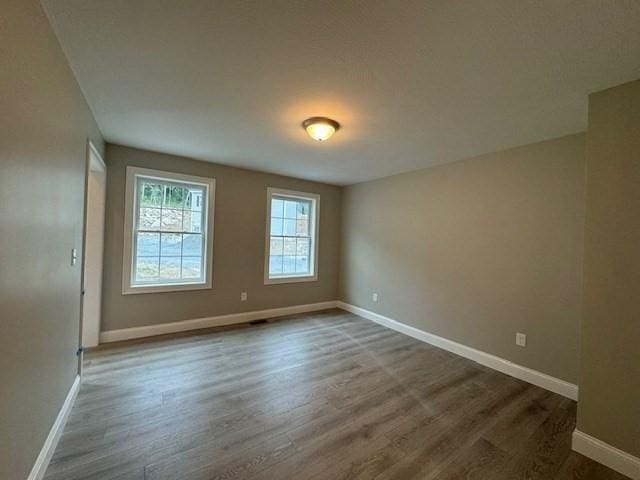 spare room with dark wood-style floors and baseboards