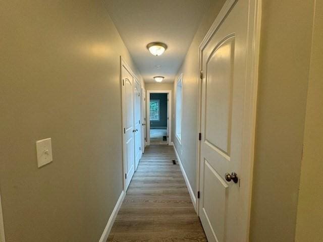 hall with baseboards and wood finished floors