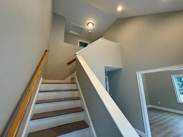 stairs with high vaulted ceiling, wood finished floors, and baseboards