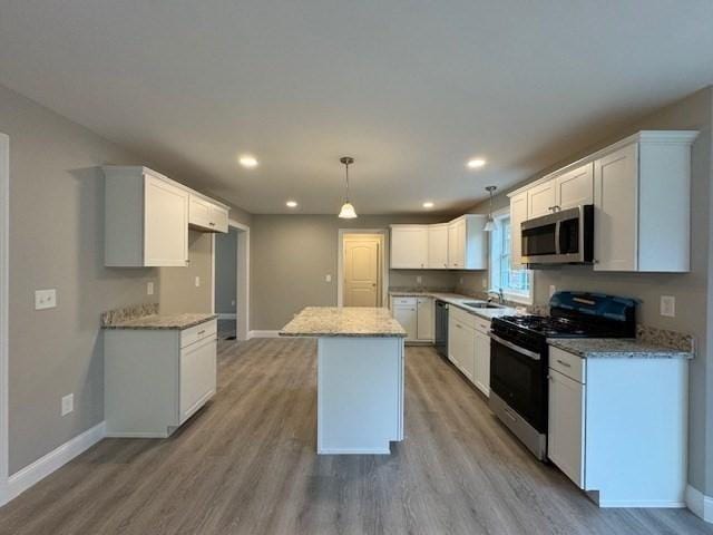 kitchen with light wood finished floors, dishwashing machine, stainless steel microwave, a center island, and black gas stove