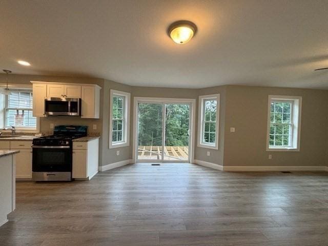 kitchen featuring stainless steel microwave, open floor plan, a sink, and range with gas cooktop