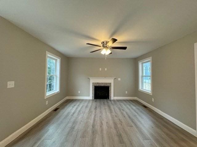 unfurnished living room with a fireplace, visible vents, ceiling fan, wood finished floors, and baseboards