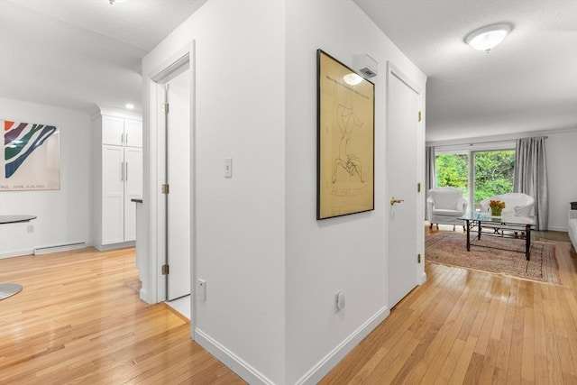 corridor featuring light wood-style flooring and baseboards