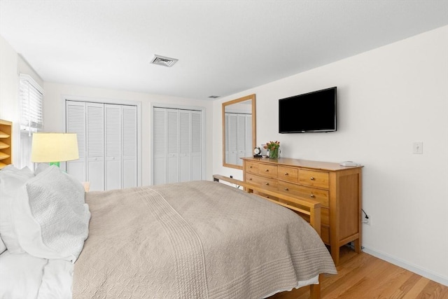 bedroom with multiple closets, wood finished floors, and baseboards