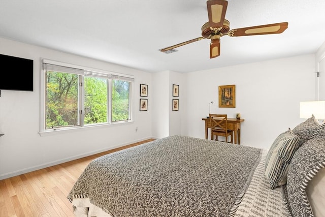 bedroom with light wood-style floors, baseboards, and a ceiling fan