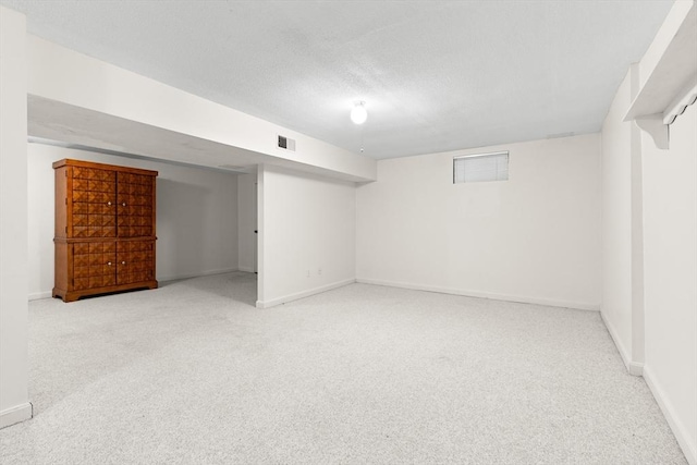 finished below grade area featuring carpet floors, baseboards, and a textured ceiling