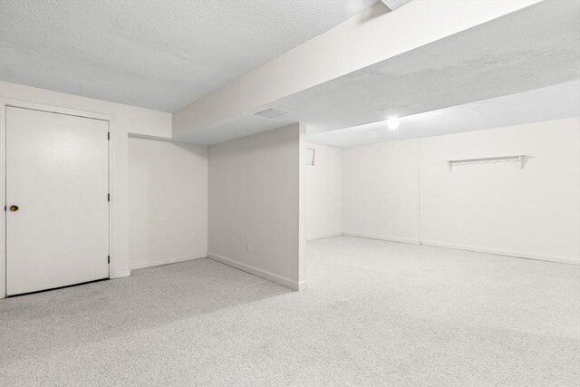 finished below grade area with baseboards, a textured ceiling, and carpet floors