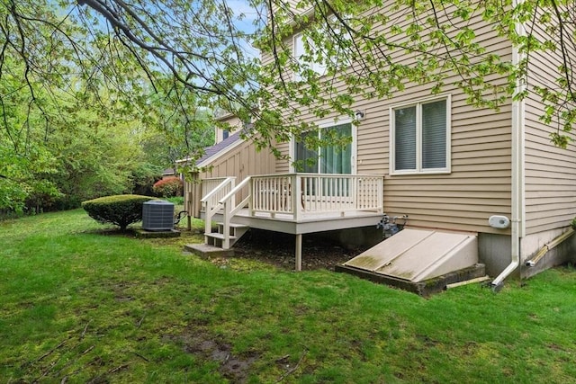 back of property featuring central AC unit, a wooden deck, and a lawn