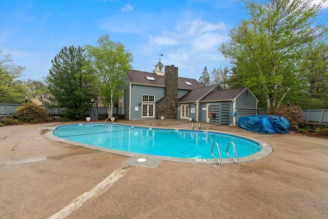 view of swimming pool with french doors, a patio, and fence
