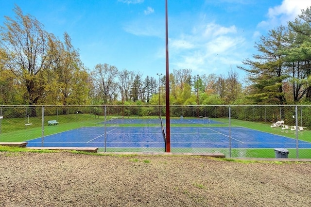view of basketball court featuring a tennis court and fence
