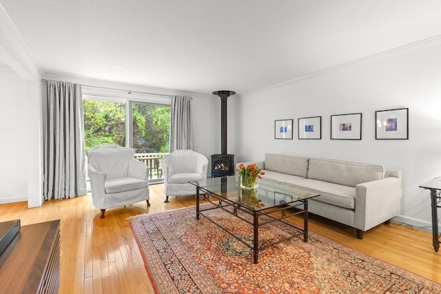 living area featuring crown molding, a wood stove, light wood finished floors, and baseboards