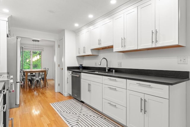 kitchen featuring appliances with stainless steel finishes, a sink, recessed lighting, white cabinetry, and light wood-type flooring