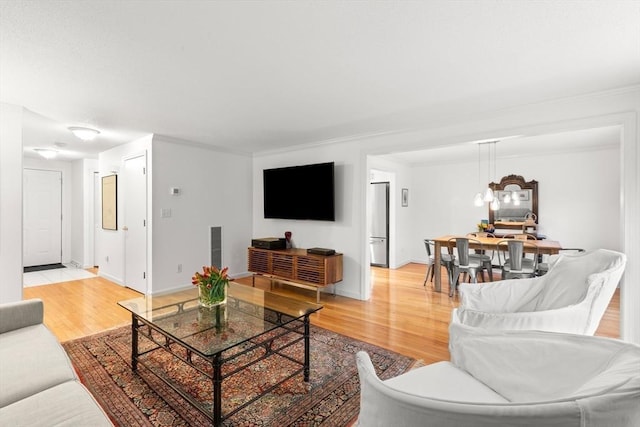 living area with light wood-style flooring, baseboards, and a chandelier