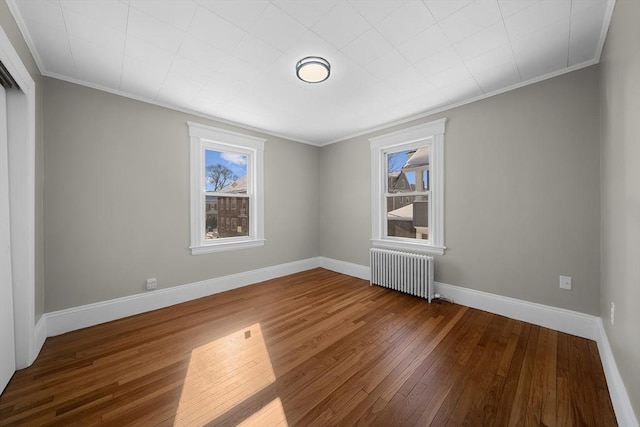 empty room with baseboards, plenty of natural light, radiator, and wood-type flooring