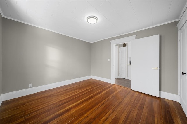 empty room featuring baseboards, crown molding, and hardwood / wood-style flooring