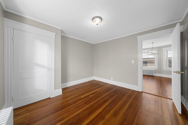 empty room with baseboards, dark wood finished floors, radiator heating unit, ornamental molding, and a notable chandelier