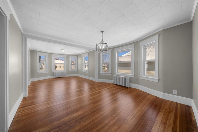 unfurnished living room with radiator, baseboards, and wood-type flooring