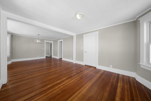 unfurnished room featuring a notable chandelier, dark wood-style floors, baseboards, and ornamental molding