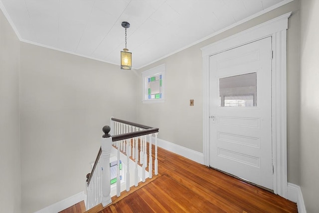 foyer entrance with crown molding, baseboards, and wood finished floors