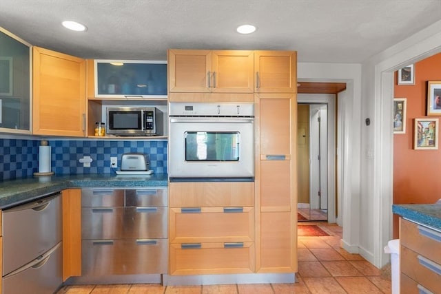 kitchen with tasteful backsplash, recessed lighting, glass insert cabinets, stainless steel appliances, and light tile patterned floors