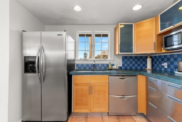 kitchen featuring dark countertops, a sink, stainless steel appliances, and tasteful backsplash