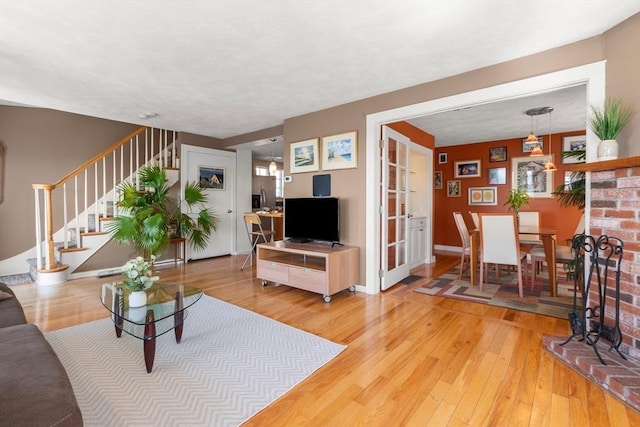 living room with baseboards, light wood-type flooring, and stairway