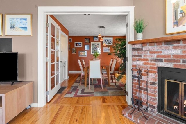 dining room featuring baseboards, visible vents, a fireplace, and light wood finished floors