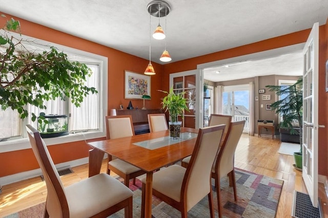 dining area featuring light wood finished floors, visible vents, and baseboards