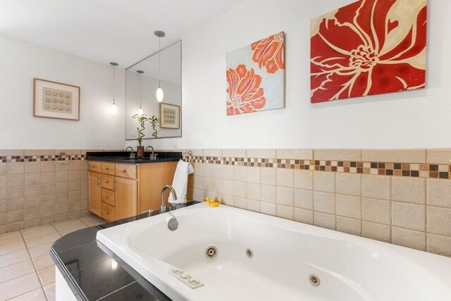 bathroom featuring tile walls, vanity, a tub with jets, tile patterned flooring, and wainscoting
