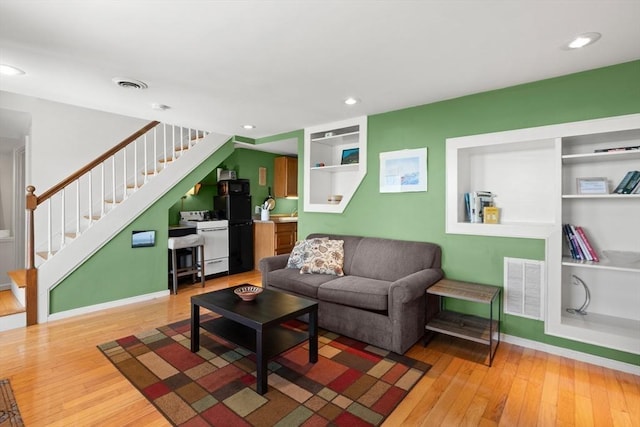 living area featuring visible vents, wood-type flooring, and stairs