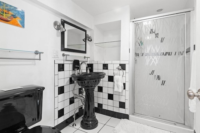 bathroom featuring a stall shower, tile walls, a sink, and tile patterned floors