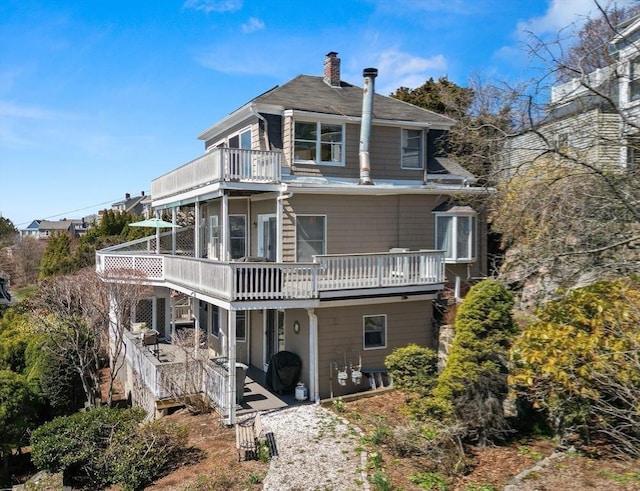 back of property featuring a deck, a chimney, and a balcony