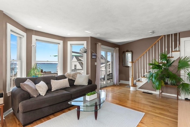 living area with baseboards, visible vents, stairway, and light wood-style floors