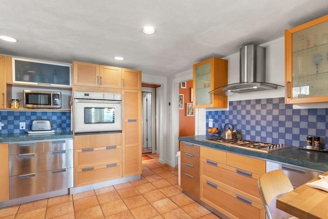 kitchen featuring wall chimney range hood, tasteful backsplash, appliances with stainless steel finishes, dark countertops, and recessed lighting