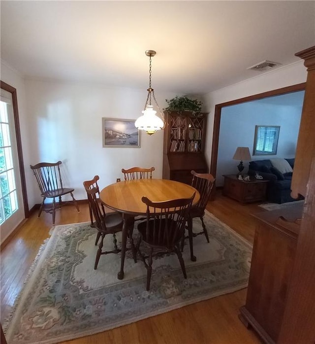 dining room with wood finished floors, ornamental molding, and visible vents