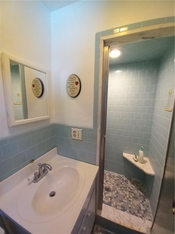 full bath with a shower stall, vanity, and tile walls