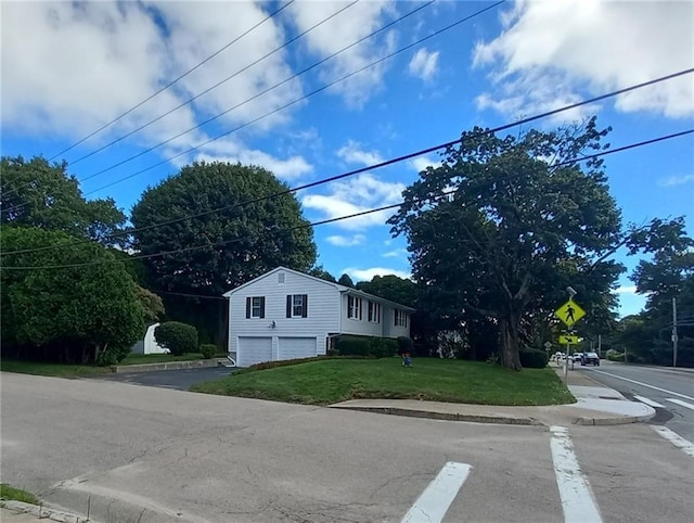 view of property exterior featuring a yard, a garage, and driveway