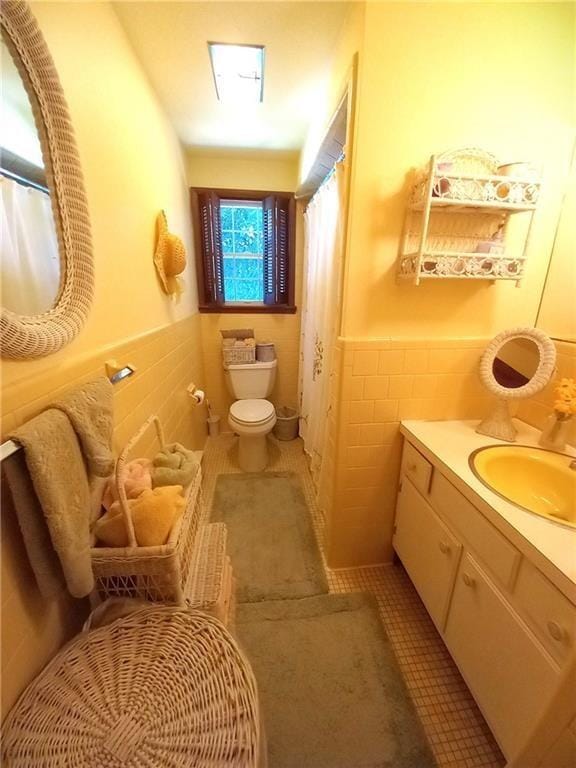 full bathroom featuring vanity, tile patterned flooring, toilet, wainscoting, and tile walls