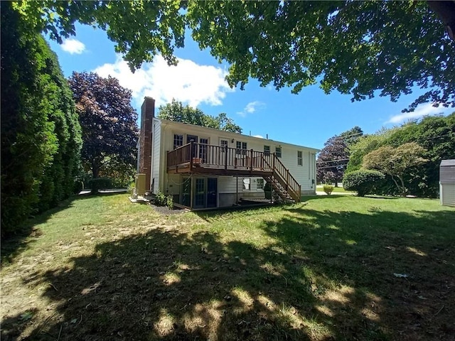 back of property with stairs, a deck, a chimney, and a lawn