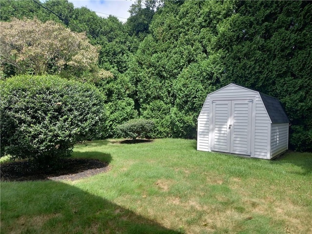 view of yard with a wooded view, an outdoor structure, and a storage unit