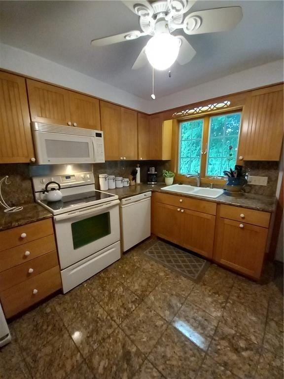 kitchen with white appliances, a ceiling fan, a sink, dark countertops, and decorative backsplash