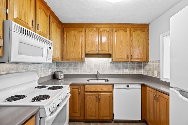 kitchen featuring sink, a textured ceiling, white appliances, and decorative backsplash