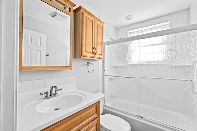 full bathroom with vanity, shower / bath combination with glass door, and toilet