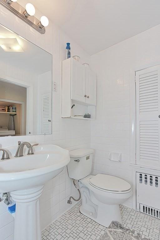 48 Tappan St, Everett, MA 02149 - bathroom featuring radiator heating unit, toilet, tile walls, tile patterned flooring, and a sink