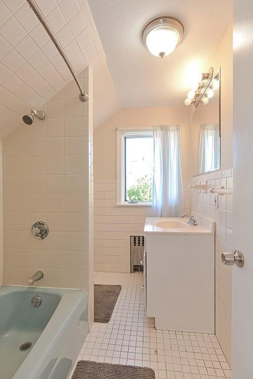 48 Tappan St, Everett, MA 02149 - full bathroom with radiator heating unit, lofted ceiling, tile walls, tile patterned flooring, and vanity