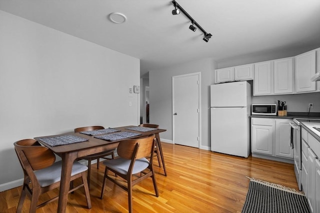 interior space with rail lighting, baseboards, and light wood-type flooring